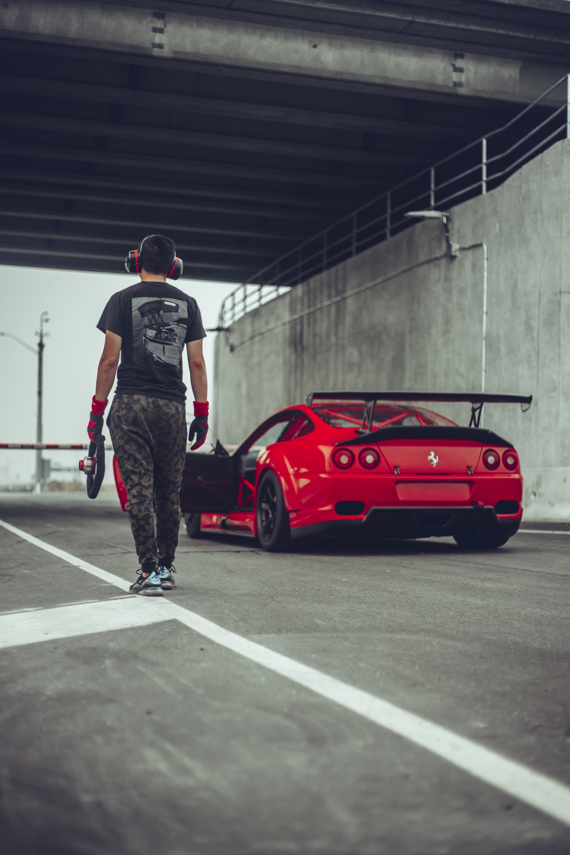 Driver approaching the Garage Saurus Ferrari 550 Maranello in the paddock