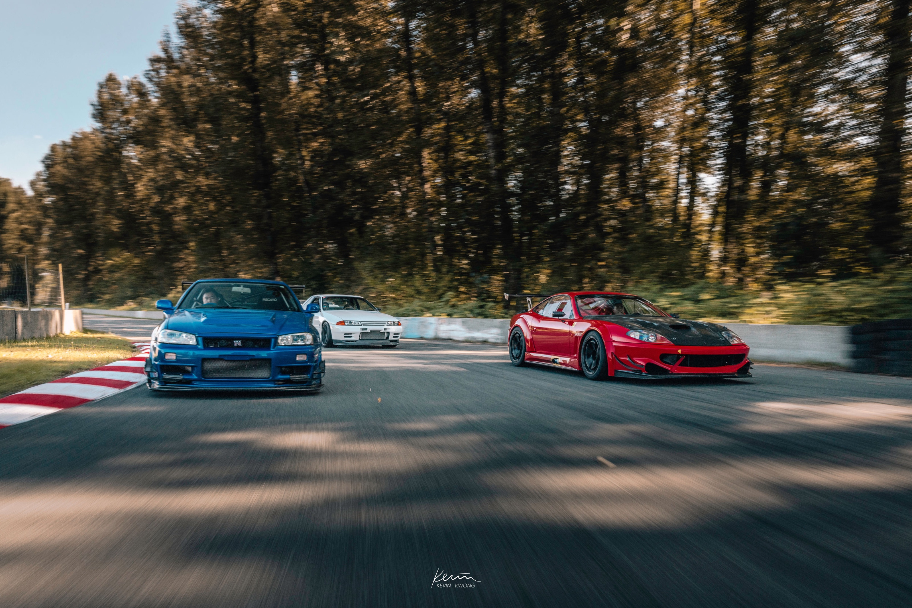 Blue Nissan Skyline GT-R R34 leading a Ferrari 550 Maranello and a white Skyline on circuit