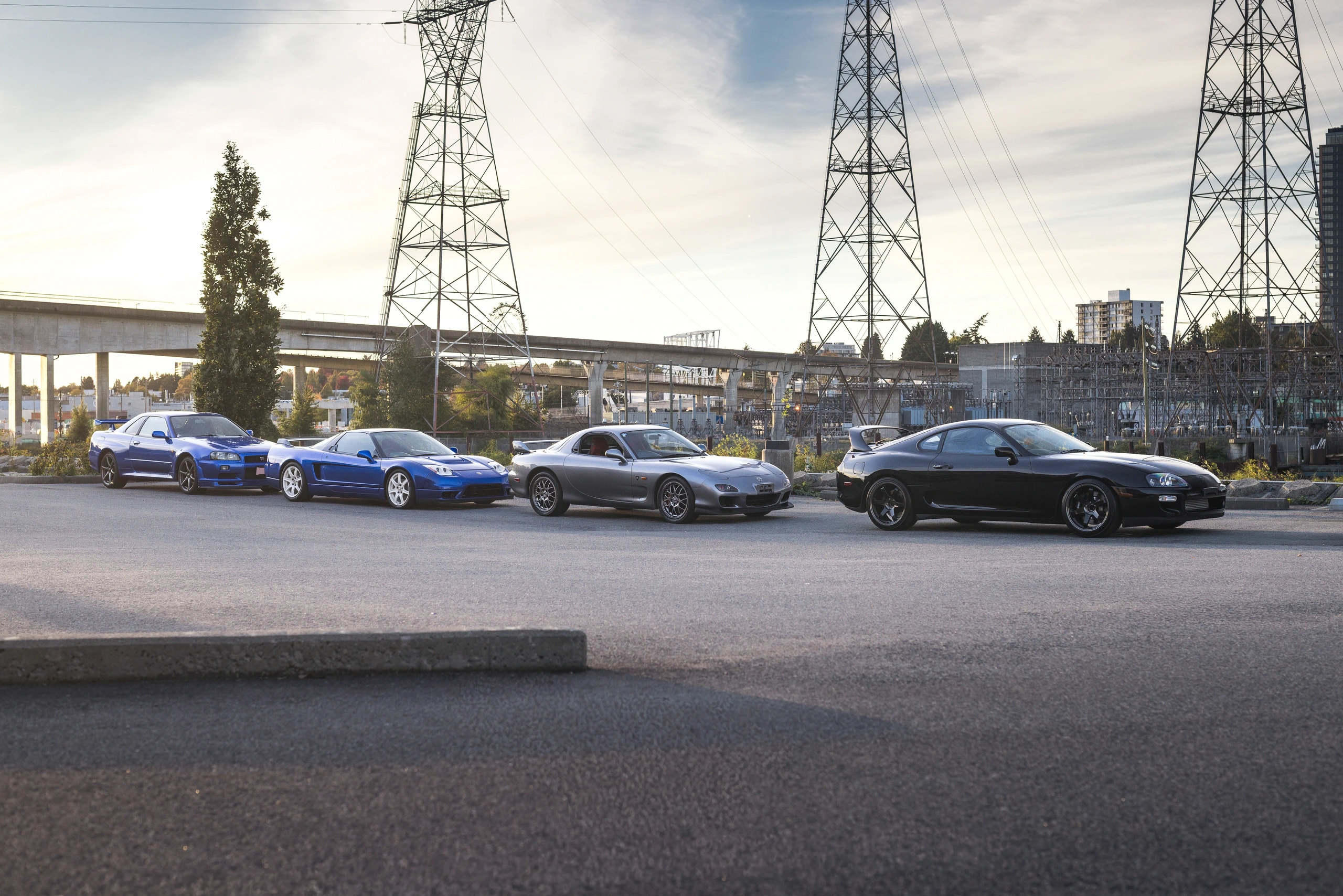 Side-by-side profiles of the Skyline GT-R, NSX-R, RX-7 and Supra against the Vancouver skyline