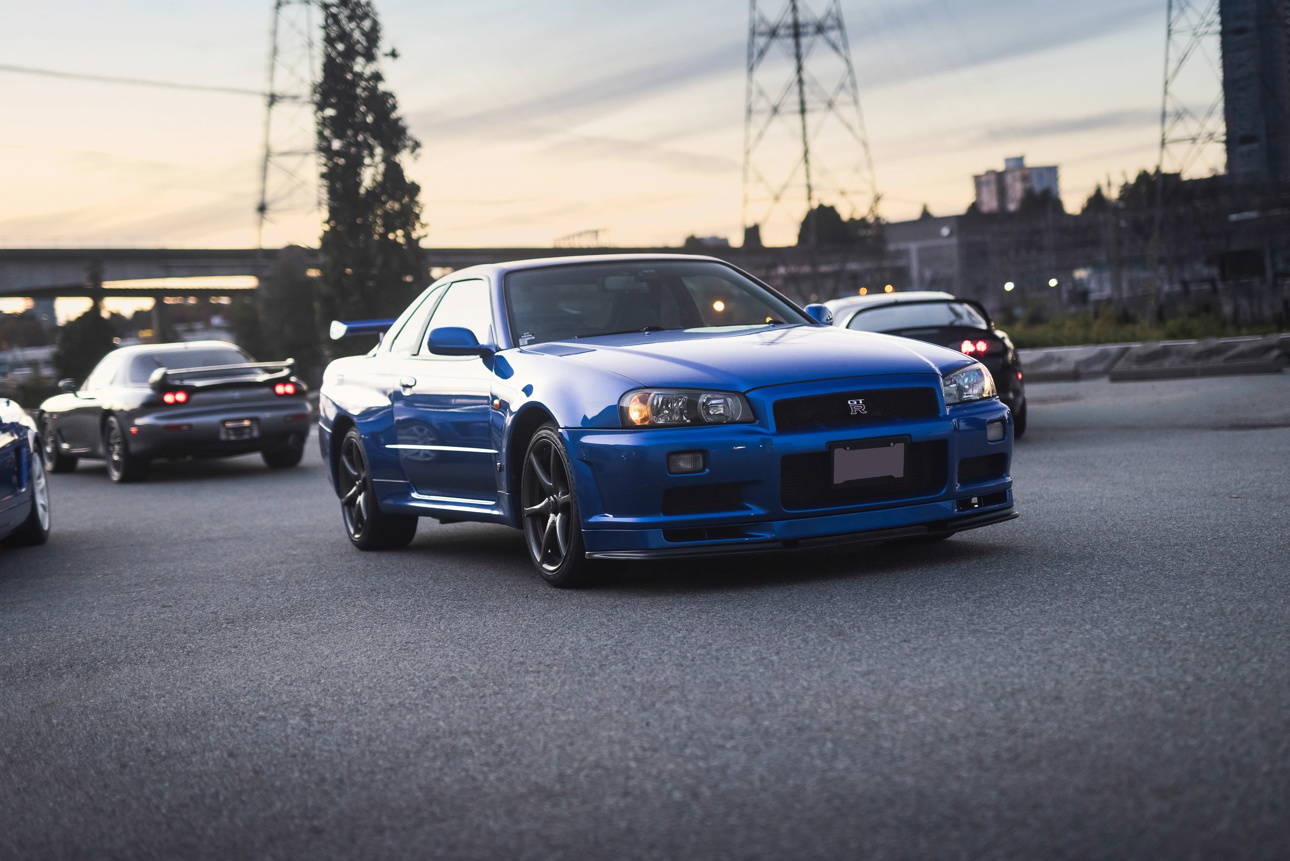 Bayside Blue R34 GT-R angled toward the camera with the other cars in the background