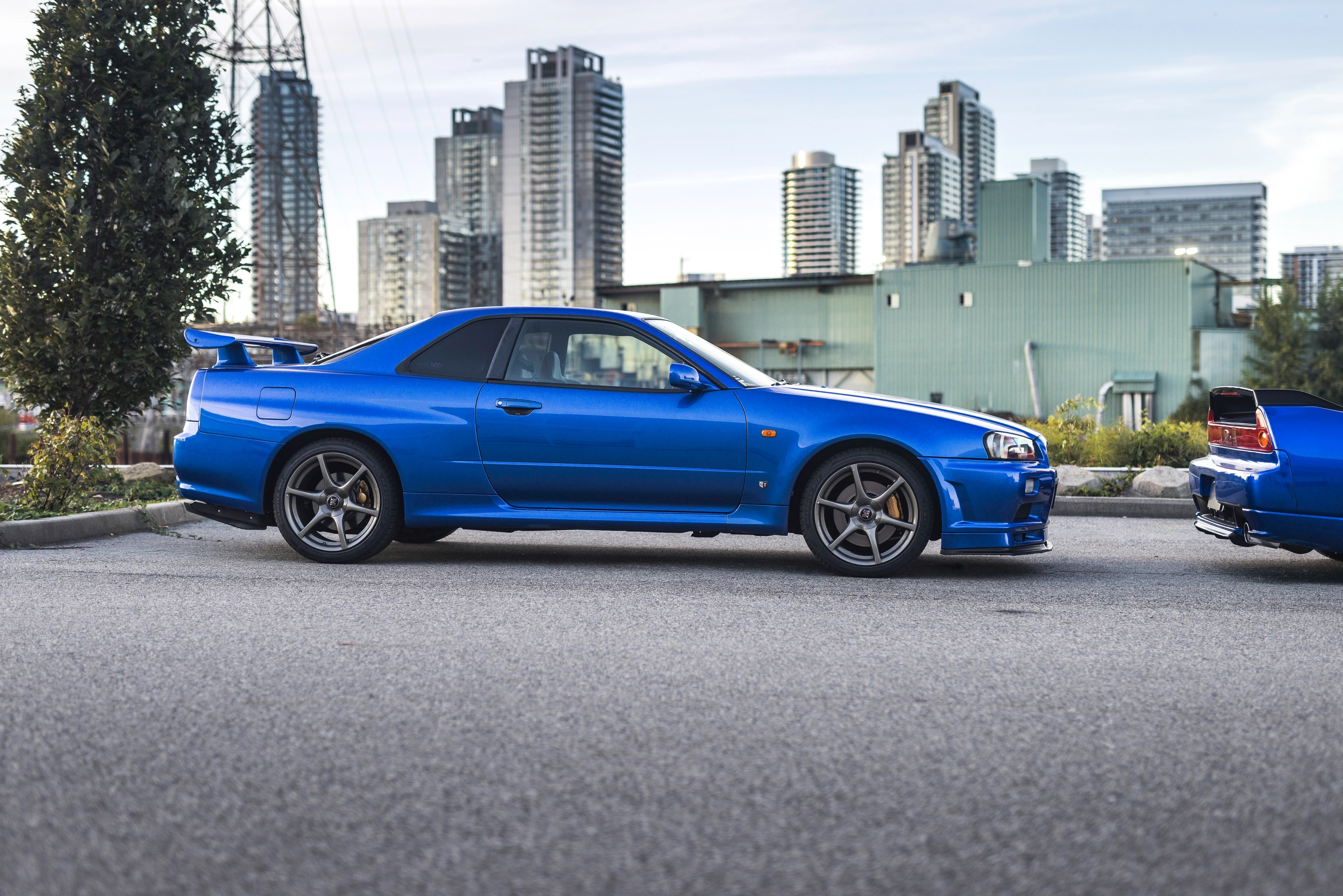 Bayside Blue R34 GT-R in side profile, showing its upright cabin and rear wing
