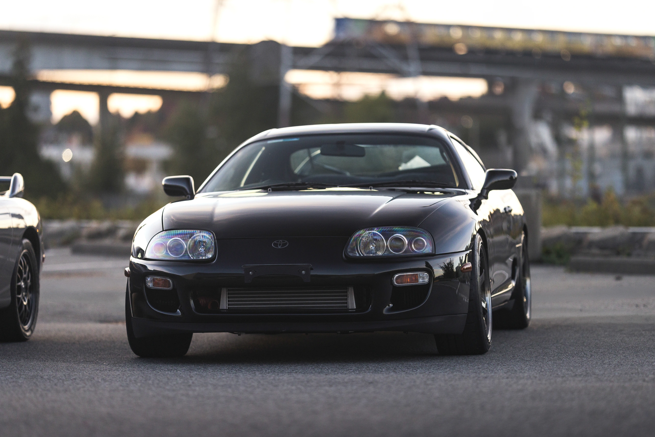 The black 1998 Supra RZ viewed head-on beneath the elevated railway
