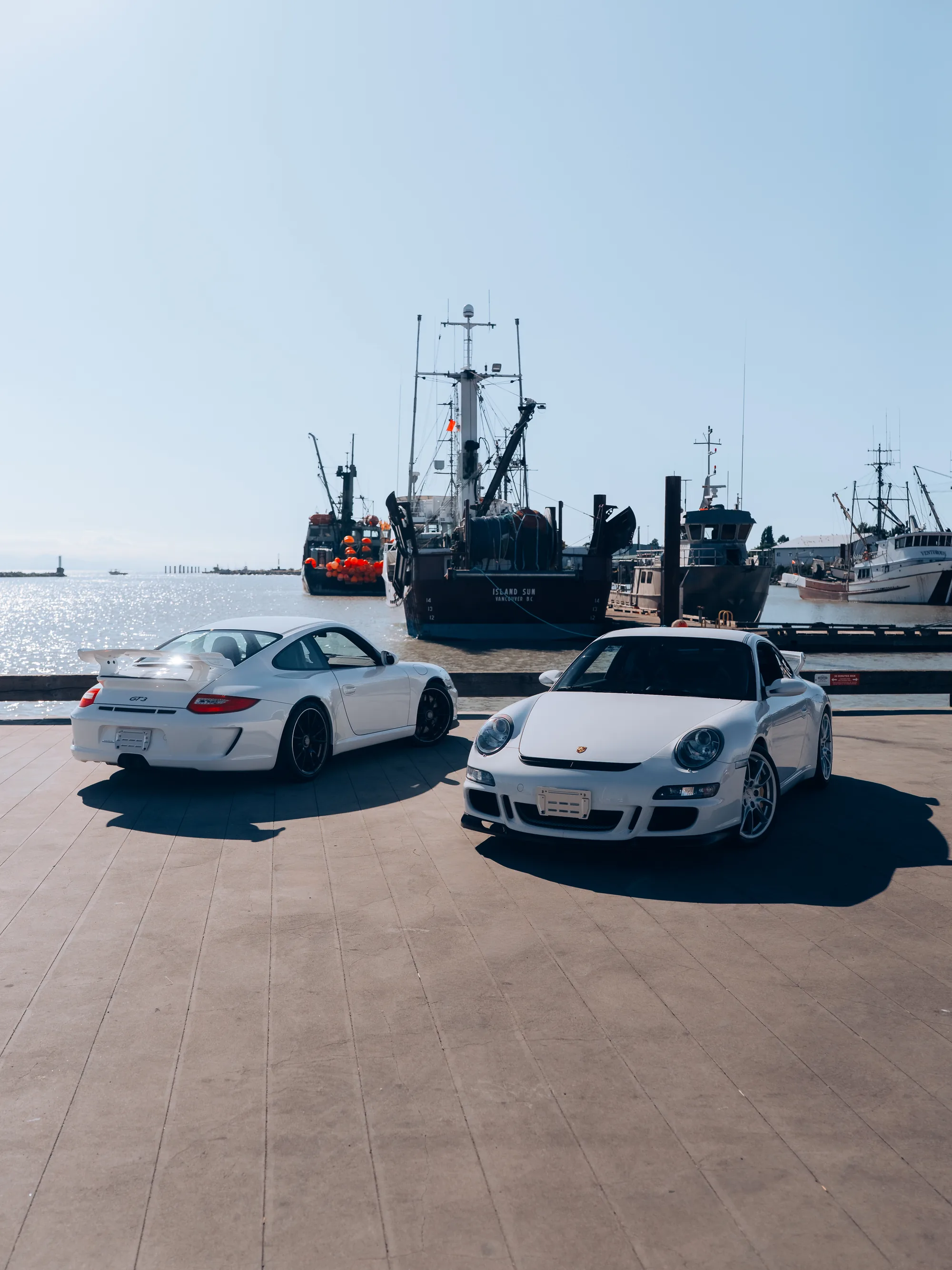 Two white Porsche 911 GT3s together at a Japanese harbour