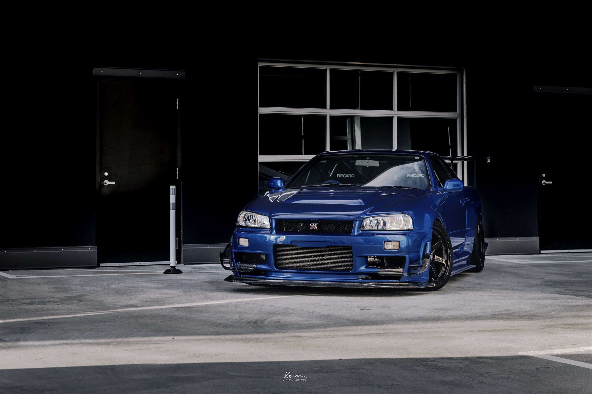 Blue Nissan Skyline GT-R R34 outside a workshop